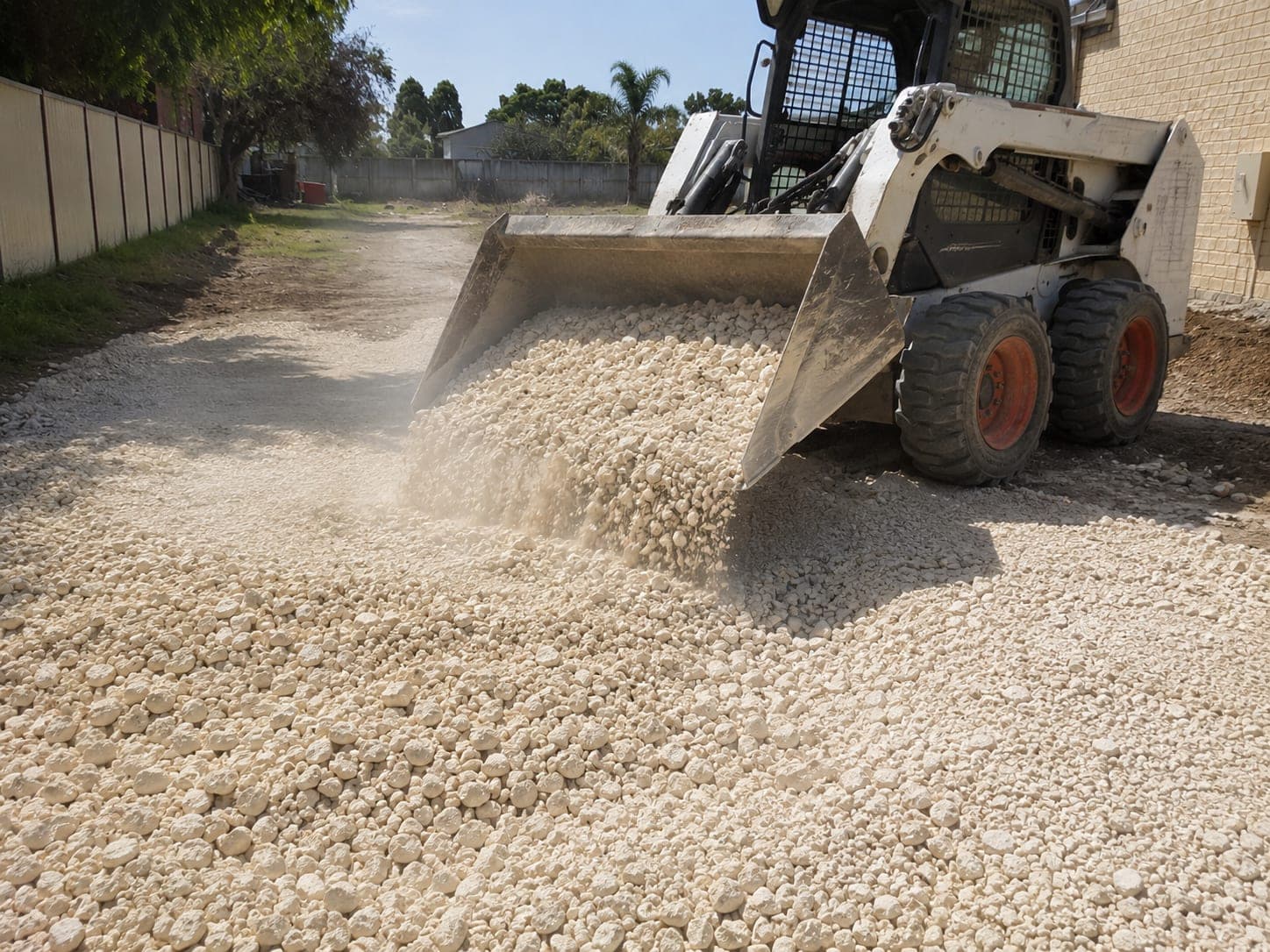 Crushed limestone base being tipped and spread for a driveway